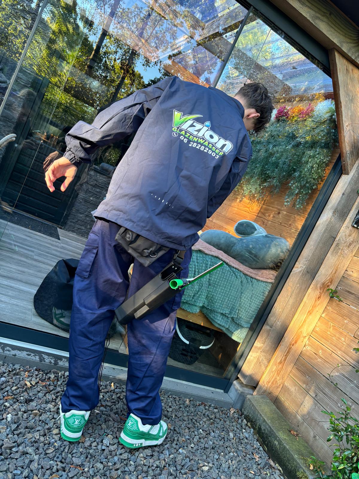 Vizion Cleaning reinigt glazen deuren in bedrijfskleding met het Vizion-logo